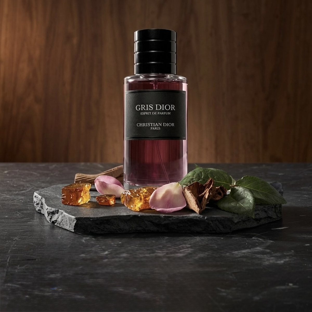 Dior Gris Dior Esprit de Parfum Parfümprobe – Flakon auf dunkler Steinplatte vor Holzwand, ringsum die Duftzutaten
