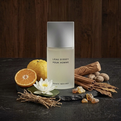 Issey Miyake L'eau d'Issey Pour Homme Parfümprobe – Flakon auf dunkler Steinplatte vor Holzwand, ringsum die Duftzutaten
